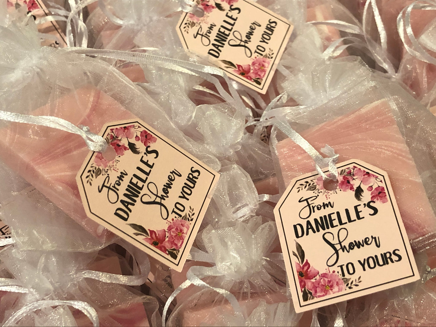Mini soap shower favors in white mesh bags with pink floral tags